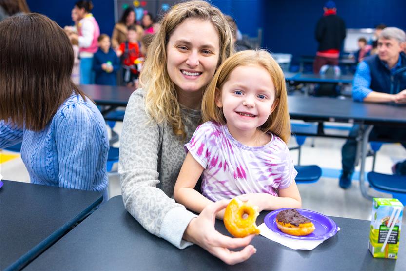 Creekside Elementary students eat donuts with a grown-up